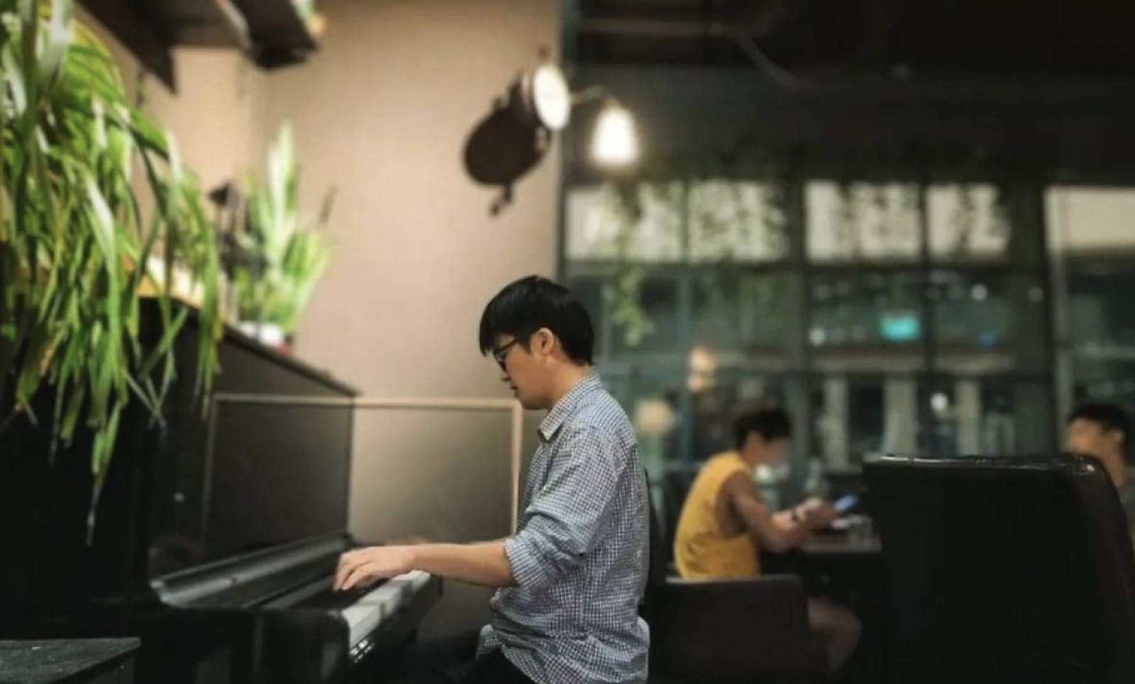 Jaeyong Kang playing an upright piano in a café